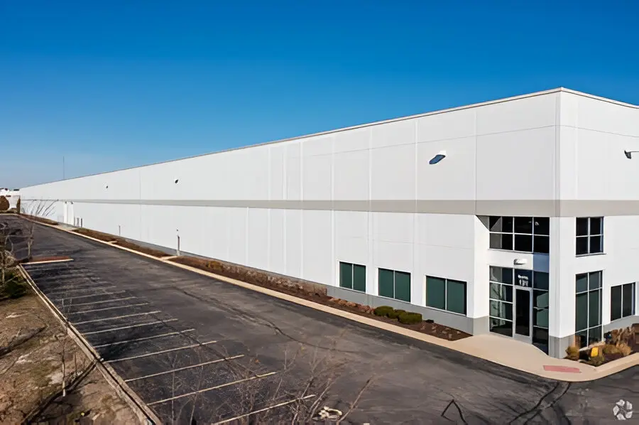 Large industrial warehouse building with parking lot.